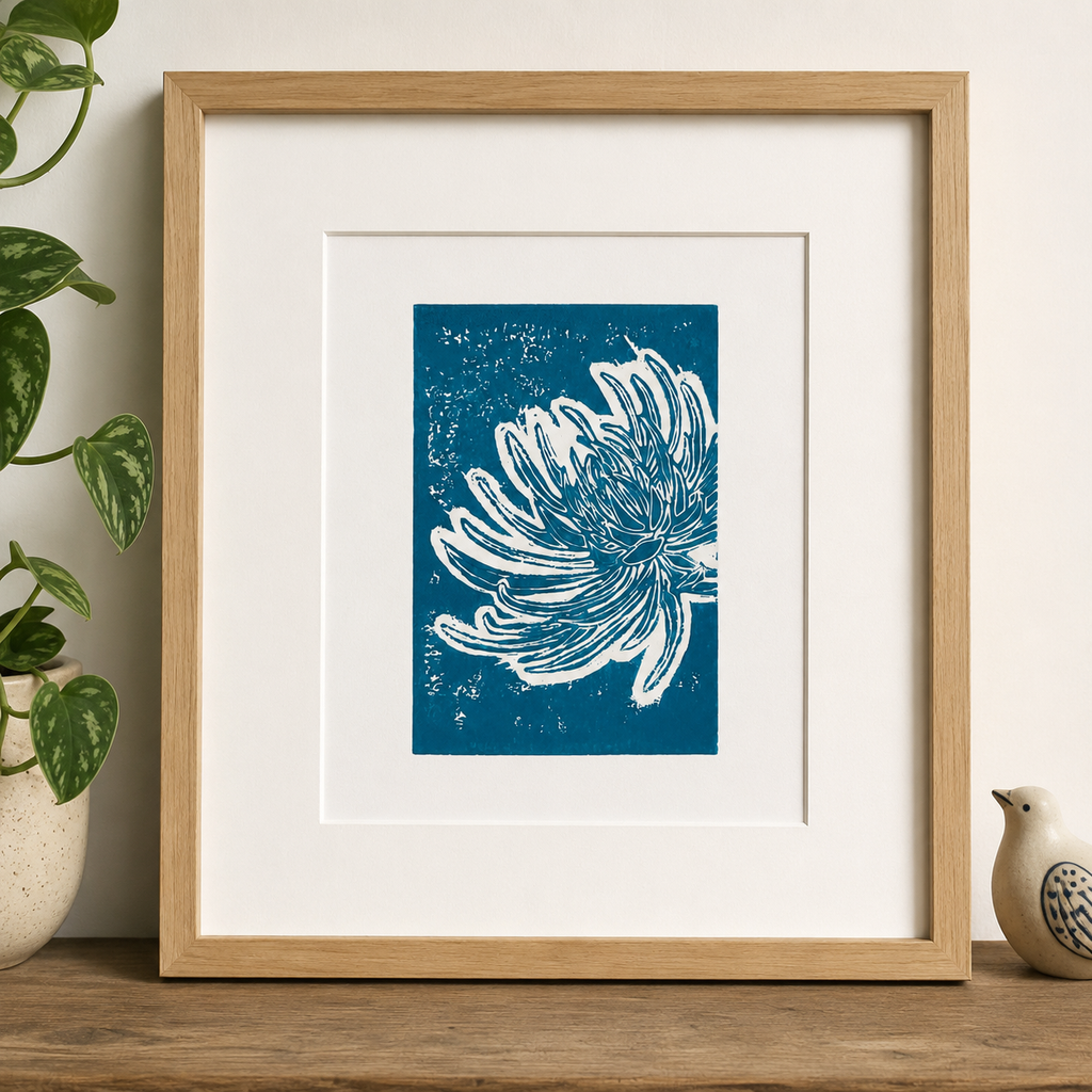 Framed linocut print of chrysanthemum flower on a shelf with a small bird and plants