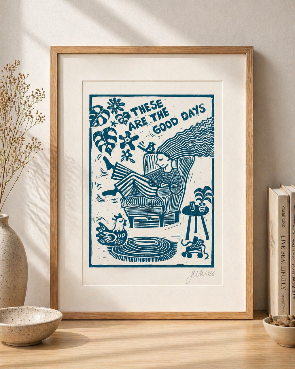 Framed artwork with blue design and text 'These are the good days' on a wooden surface.