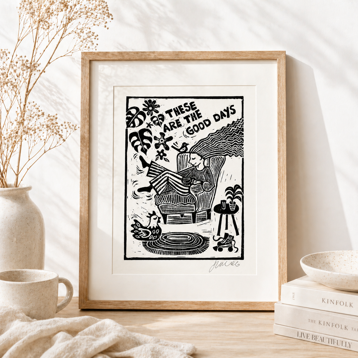 Framed black and white artwork with text on a table with decor items.