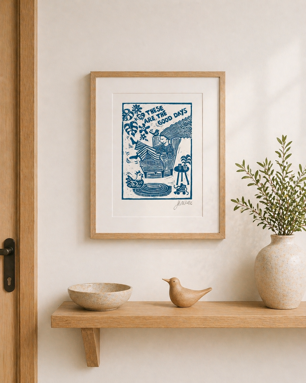 Framed artwork on a wall above a wooden shelf with decorative items.