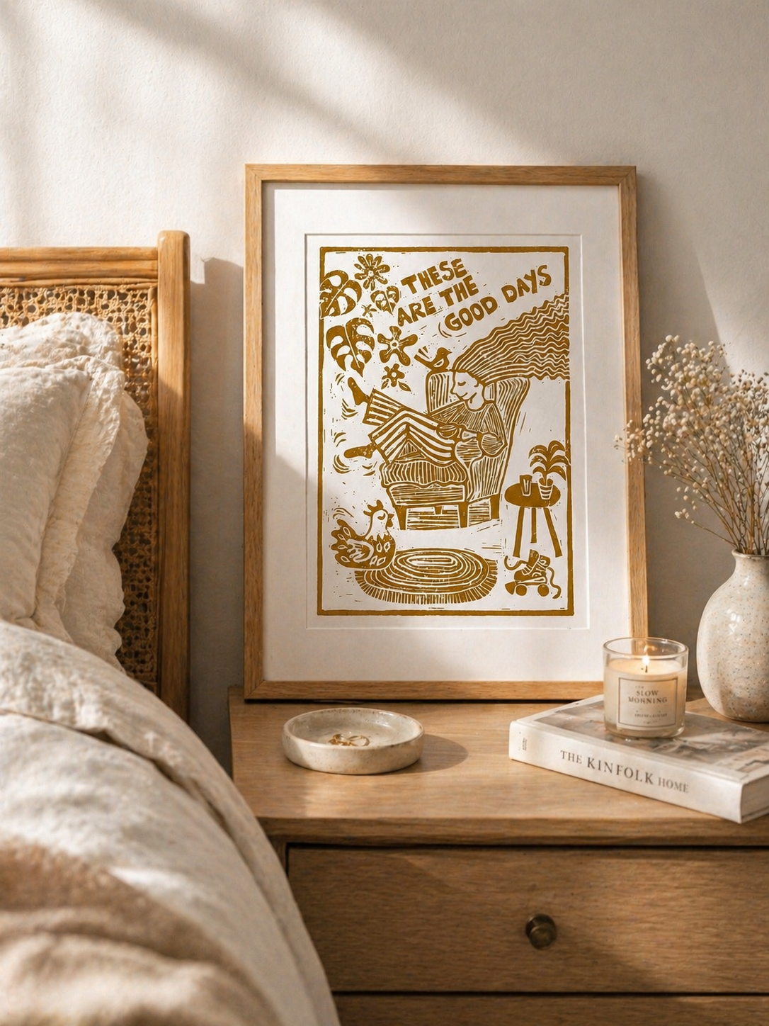 Framed artwork on a bedside table with a bed and decor in the background