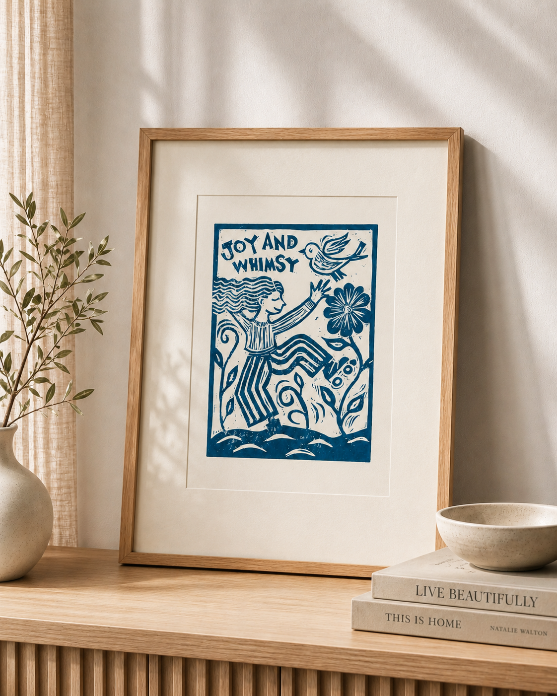 Framed artwork with 'Joy and Whimsy' text on a wooden shelf with decor items.