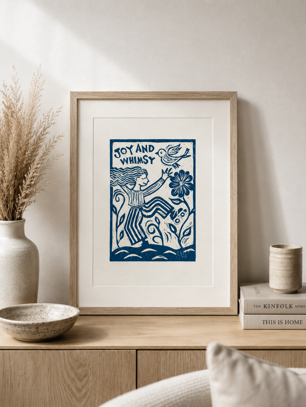 Framed artwork with blue design on a wooden shelf with decor items.