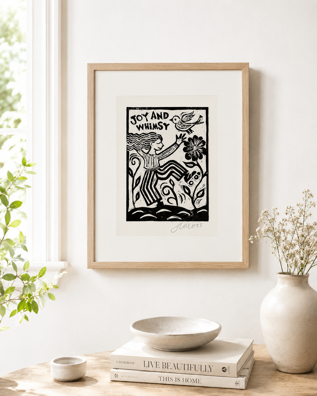 Framed artwork with a stylized illustration of a woman and text on a white wall, with decor items below.