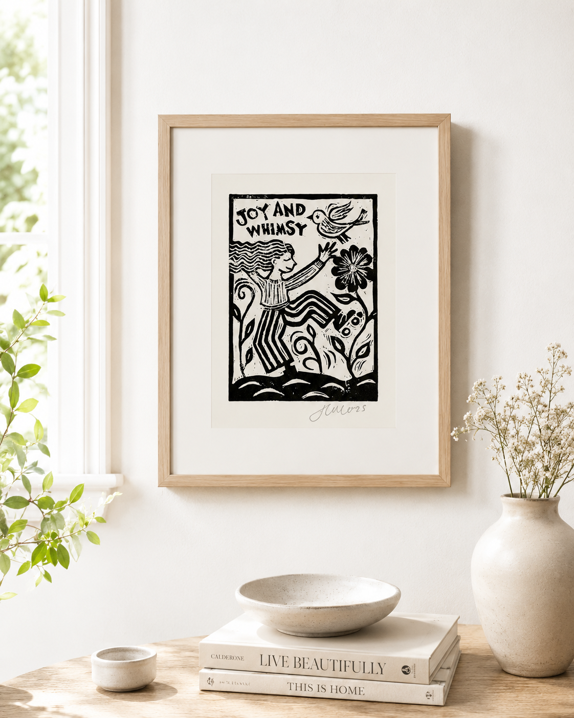 Framed artwork with a stylized illustration of a woman and text on a white wall, with decor items below.