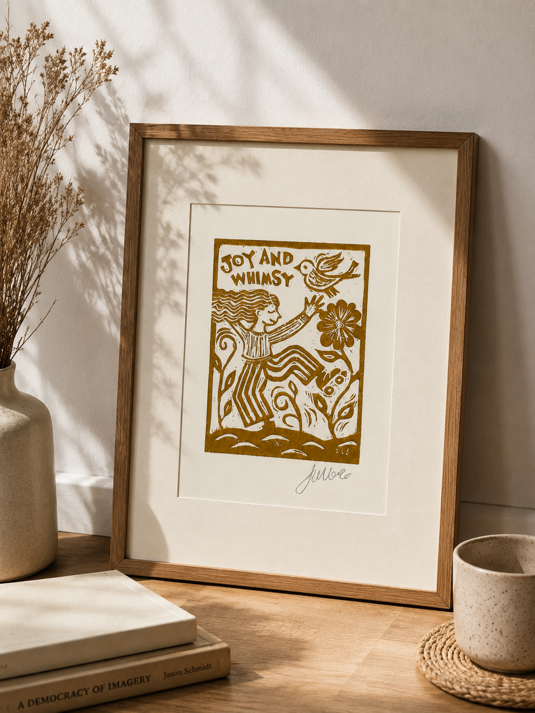 Framed artwork with 'Joy and Whimsy' text on a wooden surface with decor items.