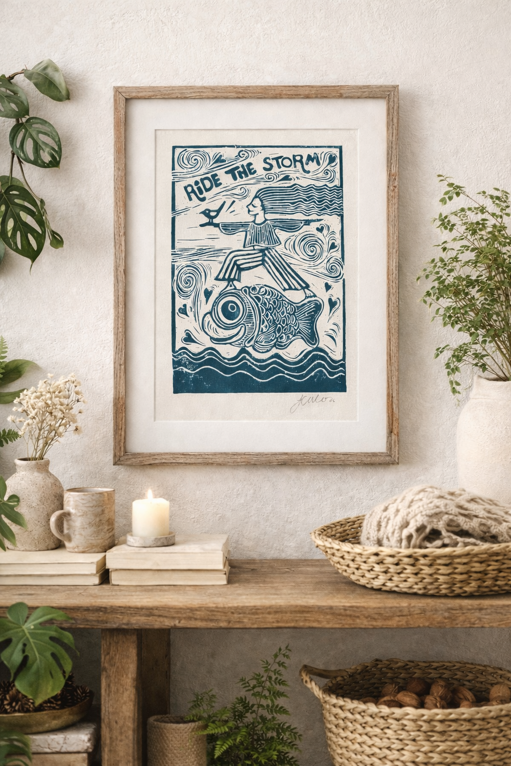 Framed artwork with a blue and white design on a wall above a wooden shelf with decor items.